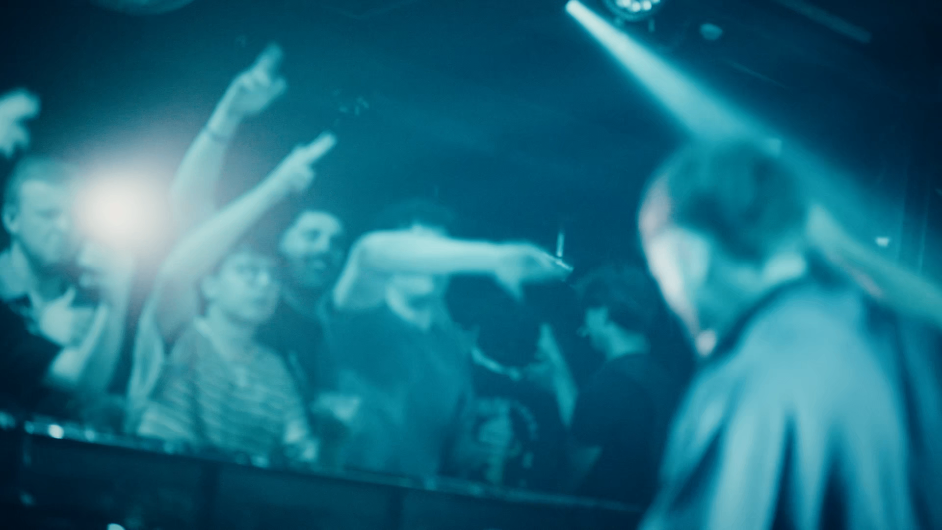 Crowd with hands in the air under club lighting